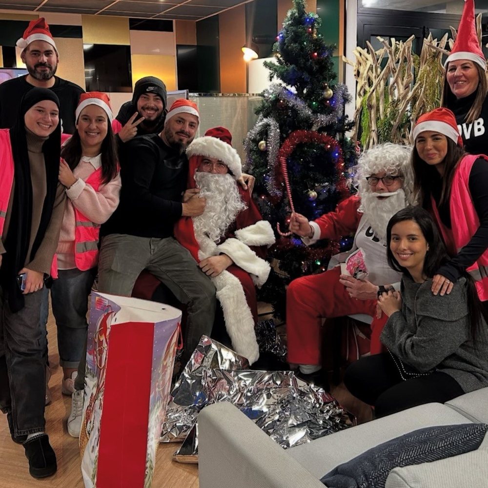 Les bénévoles de Bezons Humanity en gilets roses, réunis autour du Père Noël et du sapin, avec les cadeaux préparés pour l'opération Jouet solidaire